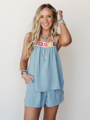 A breezy matching set in dusty sky blue — the flowy tank's granny square crochet chest panel does all the talking, paired with relaxed shorts and layered turquoise jewelry for a look that feels like summer without trying too hard.