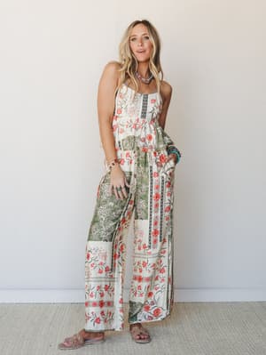 A flowy floral two-piece set in cream and sage with coral blooms, styled with turquoise and wood bead jewelry and slide sandals — the kind of outfit that makes a farmers market feel like a vacation.