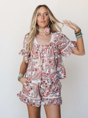 A matching paisley print top and shorts set styled with layered bracelets, a floral choker, and effortless beach waves — the kind of outfit that feels like a summer afternoon that got away from you in the best way.