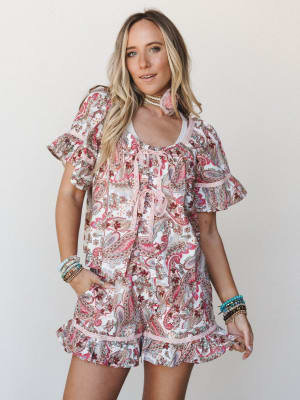 A paisley-print matching set — flowy top and ruffle-hem shorts — styled with stacked bracelets and a tassel choker for that effortless boho-summer feel.