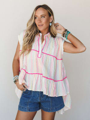 A breezy multicolor striped tiered top paired with denim shorts, styled with stacked turquoise and wood bead bracelets — the kind of summer outfit that feels effortless but clearly thought-through.