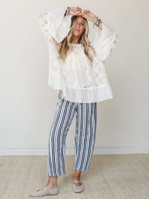A flowy lace bell-sleeve top paired with navy striped wide-leg crop pants — the kind of outfit that somehow works for both a coastal brunch and a summer evening out.