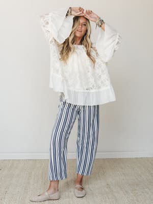 A flowy lace bell-sleeve top paired with navy striped wide-leg crop pants — the kind of outfit that somehow works for both a coastal brunch and a summer evening out.