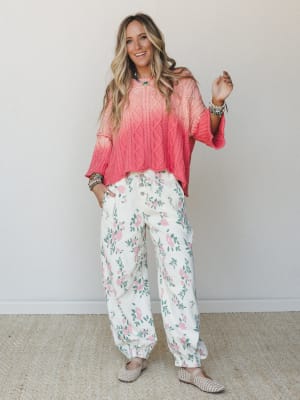 A bright, happy pairing of a coral ombré cable-knit sweater and cream floral jogger pants — the kind of outfit that makes a Tuesday feel worth dressing for.