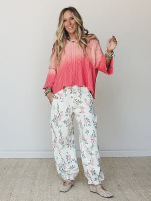 A bright, happy pairing of a coral ombré cable-knit sweater and cream floral jogger pants — the kind of outfit that makes a Tuesday feel worth dressing for.