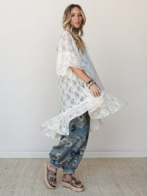 A breezy, full-length lace kimono in cream layered over floral denim joggers — the kind of outfit that looks effortless but absolutely isn't accidental.