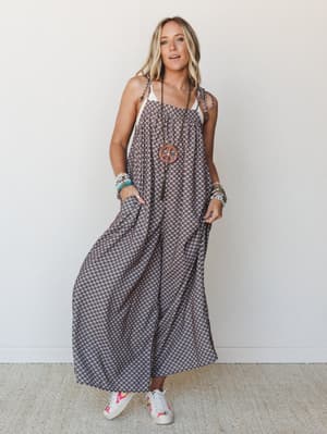 A wide-leg printed jumpsuit with relaxed, floaty volume gets styled with embroidered sneakers and a stack of colorful beaded bracelets — the kind of effortless boho outfit that looks like you didn't try but absolutely did.