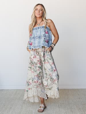 A sun-kissed boho look pairing a ruffled acid-wash denim tube top with floral embroidery against wide-leg floral pants with lace hem trim — the kind of outfit that makes you want to find a farmers market immediately.