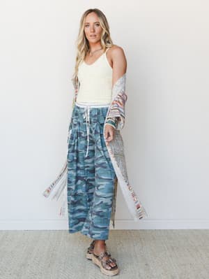 A relaxed, mix-print outfit pairing wide-leg camo pants and a cream ribbed tank under a flowing patchwork duster — the kind of effortless layering that looks intentional without trying too hard.