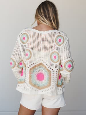 A breezy crochet top shot from the back, covered in bold granny-square medallions in cream, mint, tan, and hot pink — the kind of piece that looks handmade-with-love and pairs effortlessly with white shorts for a warm-weather day.