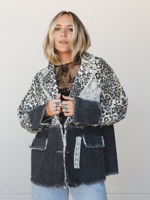 A patchwork denim blazer in washed black with a leopard print collar and sleeves, layered over a sheer lace top and light-wash jeans — the kind of jacket that does all the talking for you.
