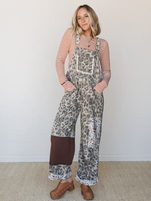 A wide-leg leopard print overall in warm tan and grey is layered over a rust stripe long-sleeve top and finished with wood-heeled clogs — the kind of mix-and-match energy that looks effortless but clearly wasn't an accident.