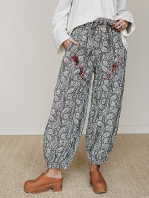 Relaxed paisley jogger pants with playful plaid pocket patches, tied at the waist and cropped with an elasticized hem — styled with an oversized cream top and wooden clogs for that effortlessly lived-in boho feel.