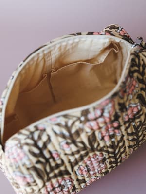 A close-up interior shot of a quilted block-print pouch bag, open and angled to reveal its natural lining and inner pocket — the kind of bag that makes you want to actually organize your life.
