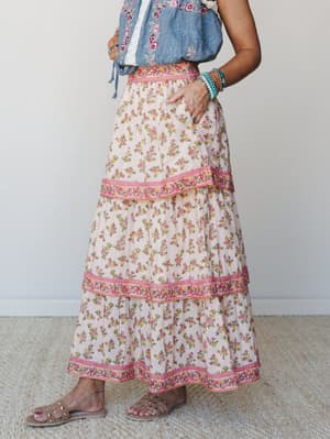 A tiered floral maxi skirt in cream with pink and yellow rose print, styled with an embroidered chambray top and strappy sandals — the kind of outfit that feels like a farmers market morning turned into something worth remembering.