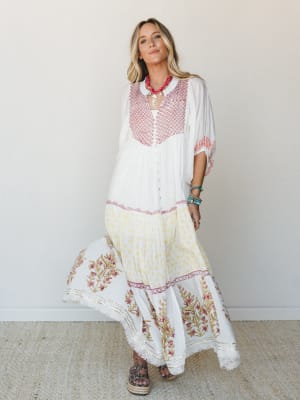 A flowy white maxi dress with block-print floral borders and a geometric embroidered bodice — the kind of dress that makes a Tuesday feel like a vacation somewhere warm.