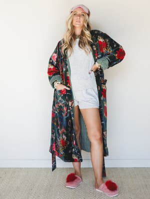 A full-length floral velvet duster layered over a striped shorts set, styled with a sleep mask and fluffy pink slippers — the kind of look that makes staying in feel like a whole mood.