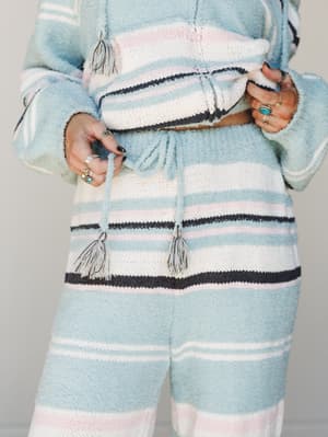 A close-up torso shot of a matching knit set in soft sky blue stripes, styled with stacked silver and turquoise rings — the kind of outfit that makes staying home feel intentional.