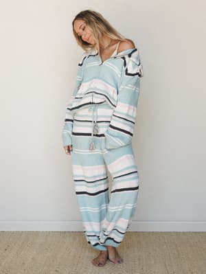 A relaxed, dreamy matching set in soft sky blue stripes — the kind of outfit that makes staying in feel intentional, worn by a model looking down with an easy, content energy.
