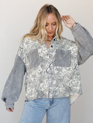 A mixed-fabric jacket with a dreamy grey paisley print body and contrasting waffle-knit sleeves, styled with light wash wide-leg jeans — the kind of layering piece that looks like it's been in your wardrobe forever.