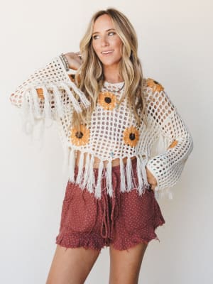 A sun-warmed crochet crop top with sunflower granny squares and fringe hem is paired with terracotta ruffle shorts — the kind of outfit that looks equally at home at a farmers market or a music festival.