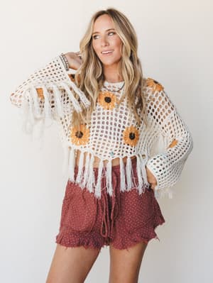 A sun-warmed crochet crop top with sunflower granny squares and fringe hem is paired with terracotta ruffle shorts — the kind of outfit that looks equally at home at a farmers market or a music festival.