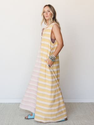 A full-length striped jumpsuit in soft mustard and blush worn with stacked turquoise bracelets and powder blue Birkenstocks — effortless and a little sun-soaked, like the first day of a trip you've been looking forward to.