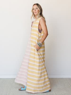 A full-length striped jumpsuit in soft mustard and blush worn with stacked turquoise bracelets and powder blue Birkenstocks — effortless and a little sun-soaked, like the first day of a trip you've been looking forward to.