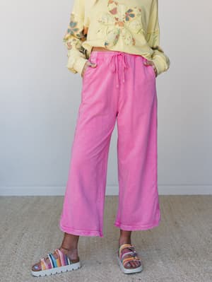 A cropped wide-leg pant in washed bubblegum pink styled with a butter yellow floral appliqué sweatshirt and multicolor platform sandals — playful, relaxed, and full of personality.