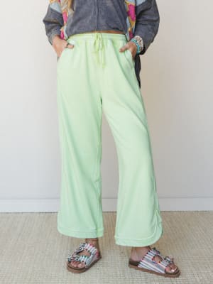 Wide-leg mint green sweat pants styled with beaded sandals and a graphic jacket — the kind of outfit that looks effortless but is clearly very much on purpose.