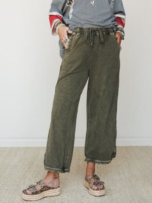 A cropped wide-leg pant in acid-washed olive styled with a striped graphic sweatshirt, leopard print platform sandals, and stacked turquoise and pearl bracelets — the kind of effortless, put-together look that feels as good as it looks.