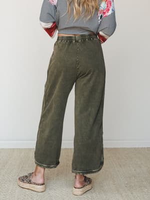 Shot from behind, this look pairs acid-washed olive wide-leg pants with a mixed-print top and leopard platform espadrilles — relaxed and expressive, like she's always this effortlessly put together.