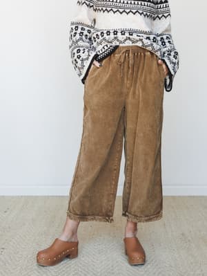 Wide-leg corduroy pants in a warm washed brown paired with a fair isle sweater and cognac studded clogs — the kind of outfit that looks pulled-together without trying.