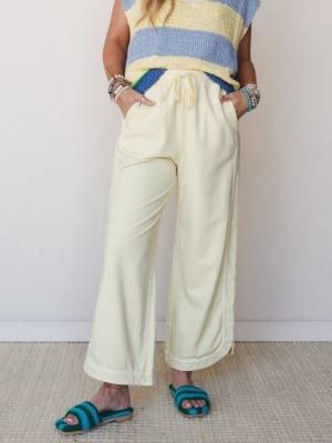 Wide-leg cropped pants in soft butter yellow styled with a color-block knit sweater vest and crochet slide sandals — relaxed and playful with a collected, effortless feel.