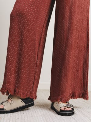 Close-up of rust patterned pants with frayed hems on a light background