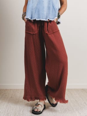 Woman wearing red patterned pants and a light blue denim shirt against a plain background