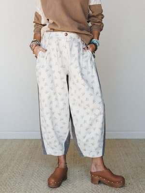 Barrel-leg floral pants styled with a layered tan sweatshirt and wooden clogs — the kind of easy, expressive outfit that feels vintage-inspired without trying too hard.