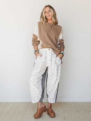 A relaxed, lived-in outfit pairing a color-block camel sweatshirt with floral wide-leg pants and brown clogs — the kind of effortless mix that looks like it took no time but absolutely did.