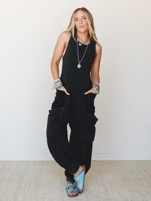 A relaxed, washed black cargo jumpsuit styled with turquoise sandals and layered boho jewelry — the kind of effortless one-and-done outfit that looks like you tried just enough.