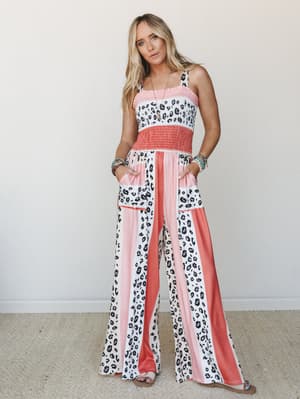 A wide-leg jumpsuit in a bold leopard and coral stripe mix, styled with layered bracelets and a delicate necklace — the kind of piece that looks effortless but definitely isn't an accident.