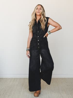A wide-leg black washed denim jumpsuit styled with stacked turquoise bracelets and tan clogs — the kind of outfit that looks effortless but definitely took a second to put together.