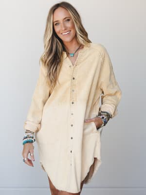 An oversized corduroy tunic dress in a soft butter-to-cream dip dye finish, styled with stacked beaded bracelets and a turquoise butterfly necklace — the kind of piece that looks like it was always yours.