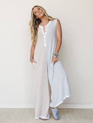 A relaxed wide-leg jumpsuit in a soft beige and blue stripe with a henley neckline — the kind of effortless piece that looks like you tried just the right amount, styled with stacked beaded bracelets and suede booties.
