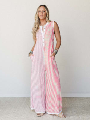 A breezy wide-leg jumpsuit in coral and white stripes worn with stacked beaded bracelets and neutral sandals — the kind of one-and-done outfit that looks like you tried just the right amount.