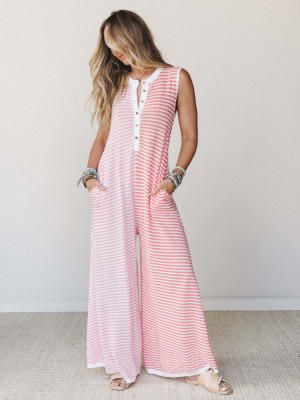 A breezy wide-leg jumpsuit in coral and white stripes styled with stacked bracelets and flat sandals — the kind of one-and-done outfit that looks like you tried just the right amount.