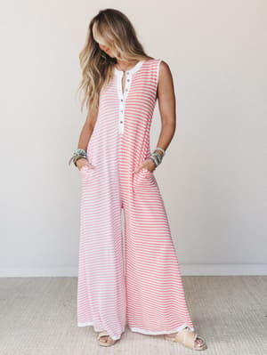 A breezy wide-leg jumpsuit in coral and white stripes styled with stacked bracelets and flat sandals — the kind of one-and-done outfit that looks like you tried just the right amount.
