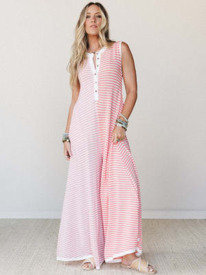 A breezy striped maxi-length wide-leg jumpsuit in coral and white, styled with stacked beaded bracelets and flat woven sandals — the kind of effortless outfit that works just as hard at brunch as it does at the beach.