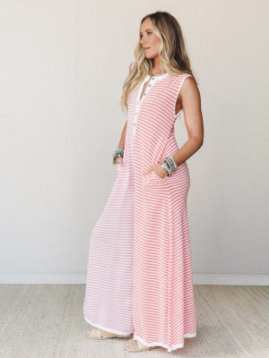 A breezy striped maxi jumpsuit in coral and white worn with stacked beaded bracelets and flat sandals — the kind of effortless one-and-done outfit that looks like you tried just enough.