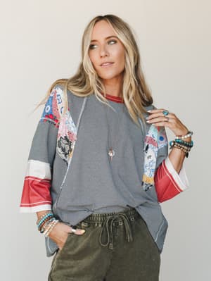 A relaxed patchwork top in navy stripe with colorful mixed-print sleeves is styled with olive drawstring pants and stacked turquoise bracelets — the kind of outfit that looks effortless but clearly has a point of view.