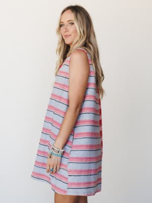 A relaxed striped mini dress in heathered grey and dusty red worn from a side angle, styled with stacked beaded bracelets and a turquoise ring — easy, warm-weather energy with a casual boho twist.